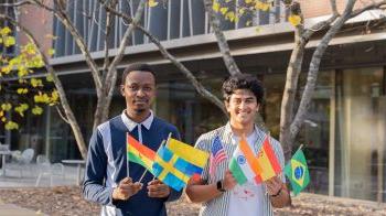 Two students, Satvik Chethan and Jim Appiah, holding several small flags of different nations.