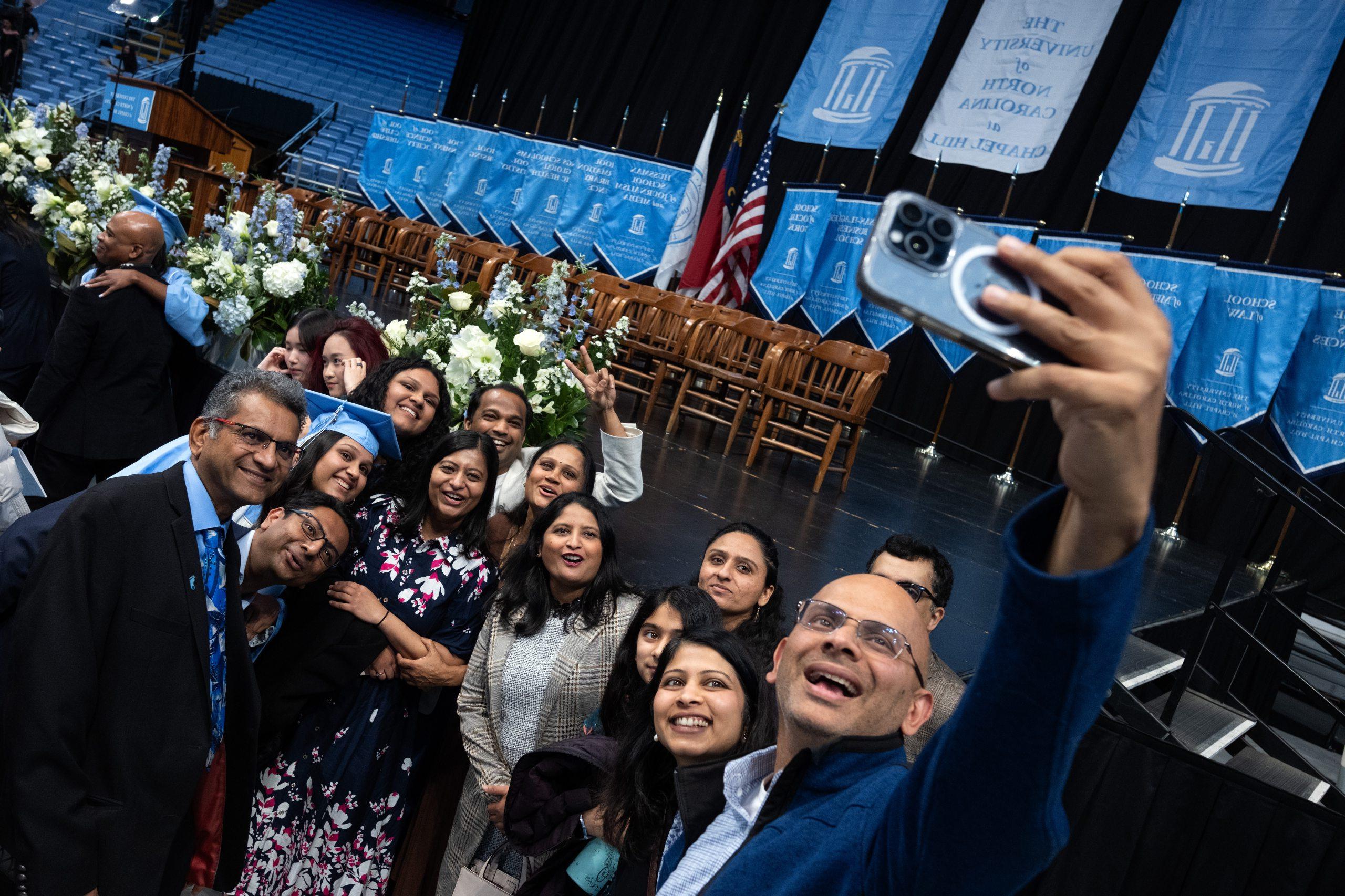 Individuals taking selfie in front of commencement stage. 